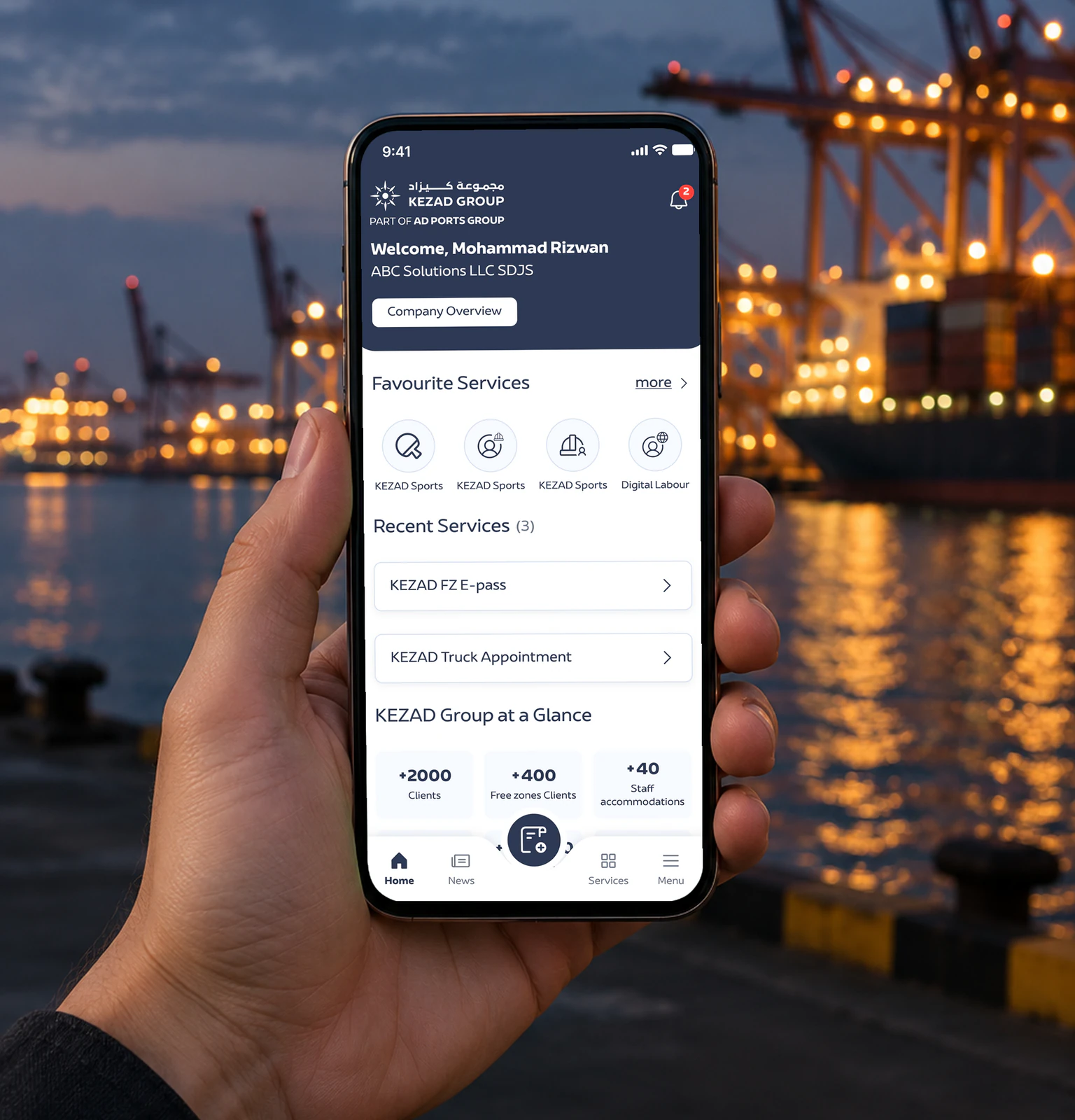 The KEZAD app home screen on a phone held in front of a port at dusk